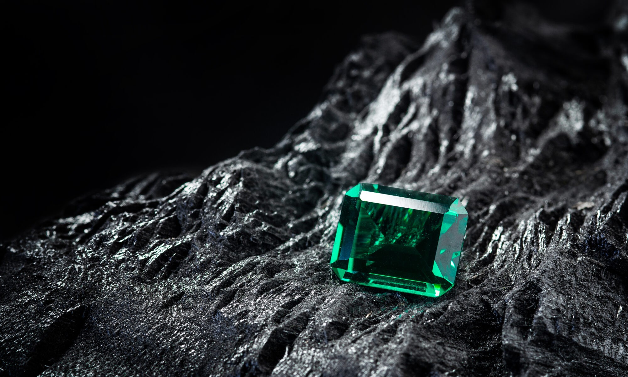 Cut emerald gem on rock